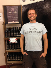 Dean smiling in front of a store display of Astrolabe beer by New Republic Brewing