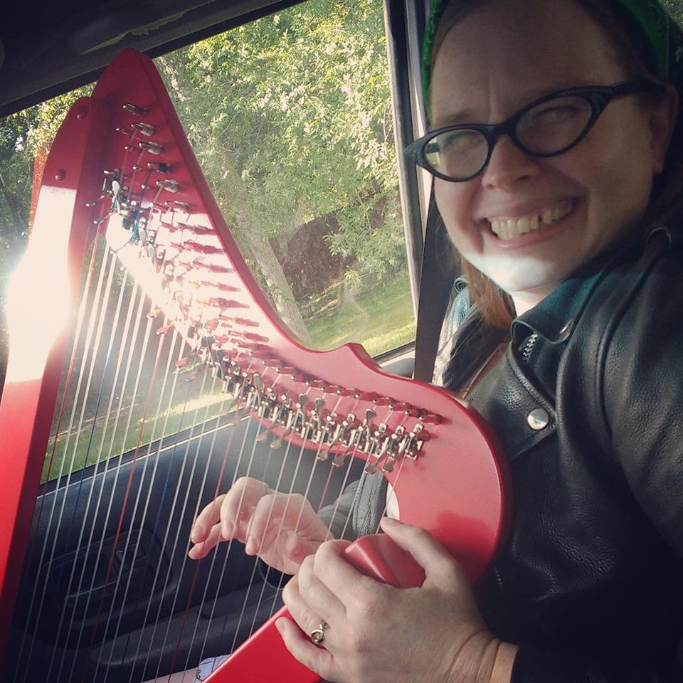 Adrienne playing a red lap harp
